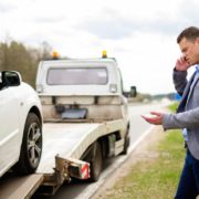 Man calling while tow truck picking up his broken car